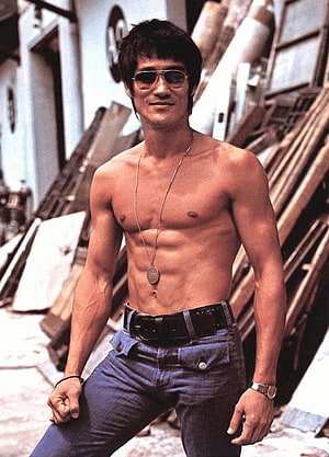 Bruce Lee shirtless portrait wearing aviator sunglasses and dog tags in an urban alley setting HD phone wallpaper