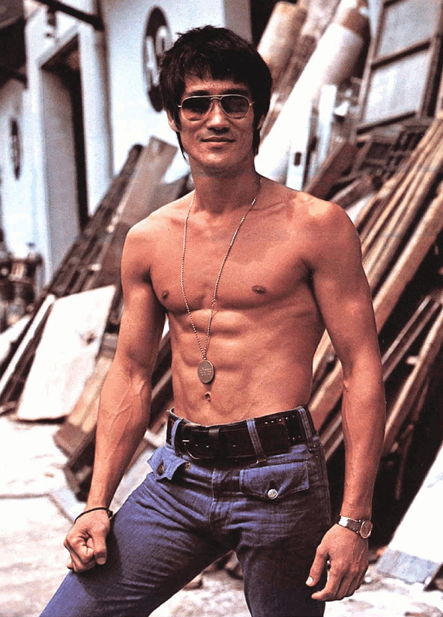 Bruce Lee shirtless portrait wearing aviator sunglasses and dog tags in an urban alley setting HD phone wallpaper