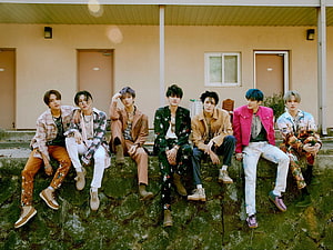 NCT DREAM Members in Colorful Streetwear Sitting on Mossy Stone Wall HD wallpaper