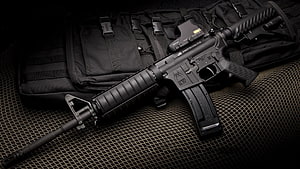 Black Tactical Rifle with Red Dot Sight Resting on Military Gear and Mesh Surface HD wallpaper
