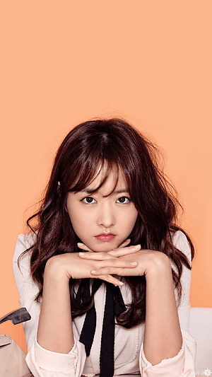 Park Bo Young Portrait in White Blouse with Black Ribbon Against Warm Orange Background HD phone wallpaper