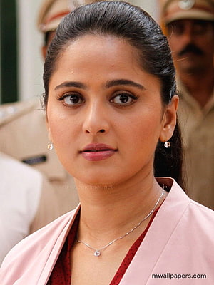 Anushka Shetty in a pink blazer with elegant jewelry and a serious expression HD phone wallpaper