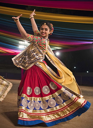 Woman performing traditional Garba dance in vibrant red and gold attire during Navratri festival in Gujarat HD phone wallpaper