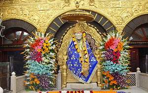 Shirdi Sai Baba Temple Idol Adorned With Blue Garments And Vibrant Flower Arrangements HD wallpaper