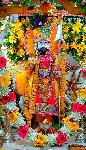 Ornate Ramdev Ji Murti Adorned With Marigold Garlands And Sacred Trishul HD phone wallpaper