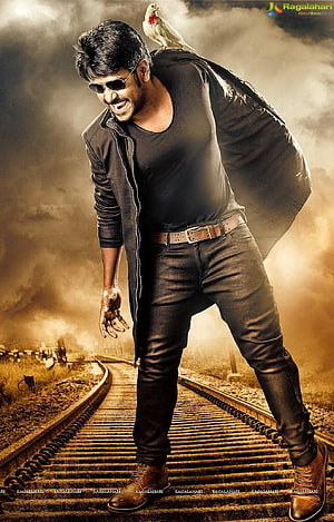 Raghava Lawrence in a dramatic action pose on railway tracks with a white parrot perched on his shoulder HD phone wallpaper