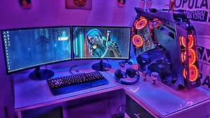 Neon-lit dual monitor gaming desk with RGB PC tower and mechanical keyboard HD wallpaper