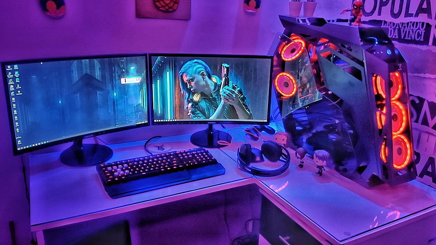 Neon-lit dual monitor gaming desk with RGB PC tower and mechanical keyboard HD wallpaper