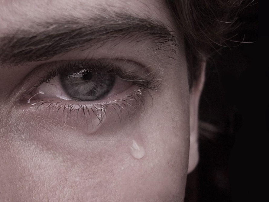 Close-up of a young man's eye with a single tear rolling down his cheek in a moody portrait HD wallpaper