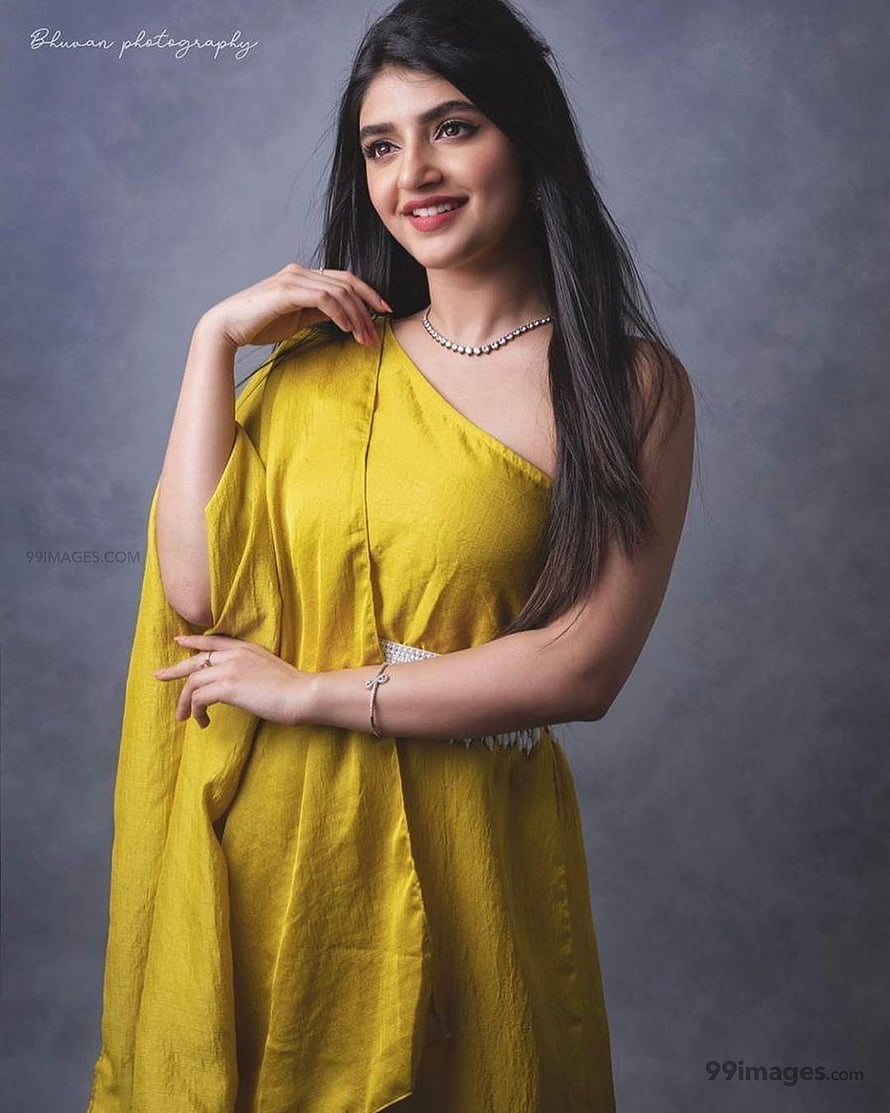 Sree Leela in a mustard yellow one-shoulder dress with long dark hair and elegant jewelry HD phone wallpaper