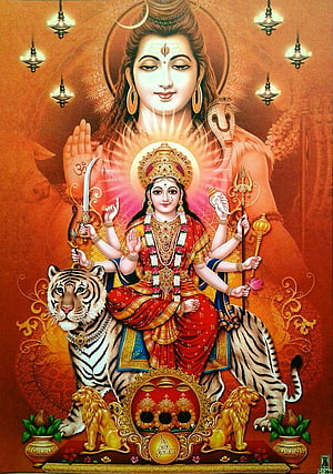 Maa Durga seated on a tiger with multiple arms holding sacred weapons and a glowing divine aura HD phone wallpaper