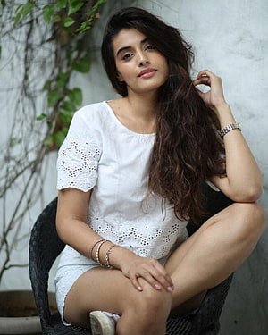 Divyansha Kaushik in a White Eyelet Top Seated in a Wicker Chair HD phone wallpaper