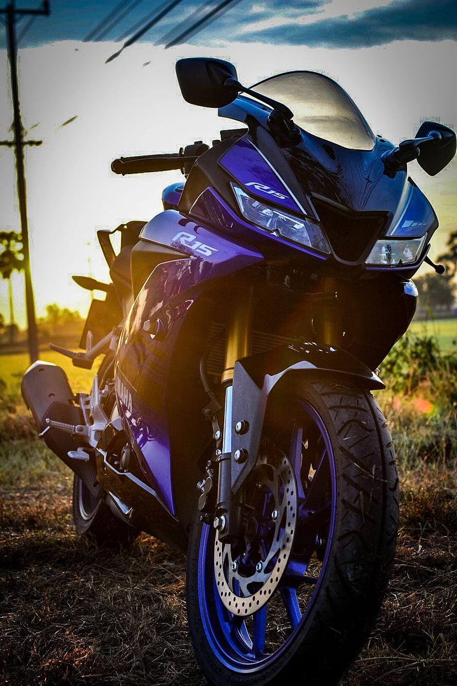 Yamaha R15 V3 sport motorcycle parked in a field at sunset with dramatic backlighting HD phone wallpaper