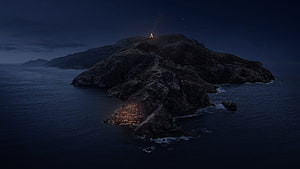 Solitary Island at Night with Distant Campfire Glow and Starry Sky HD wallpaper
