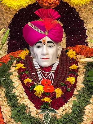 Shri Gajanan Maharaj adorned in vibrant floral garlands and a traditional pink turban HD phone wallpaper