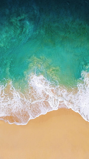 Aerial View of Turquoise Ocean Waves Lapping Against Golden Sandy Beach HD phone wallpaper