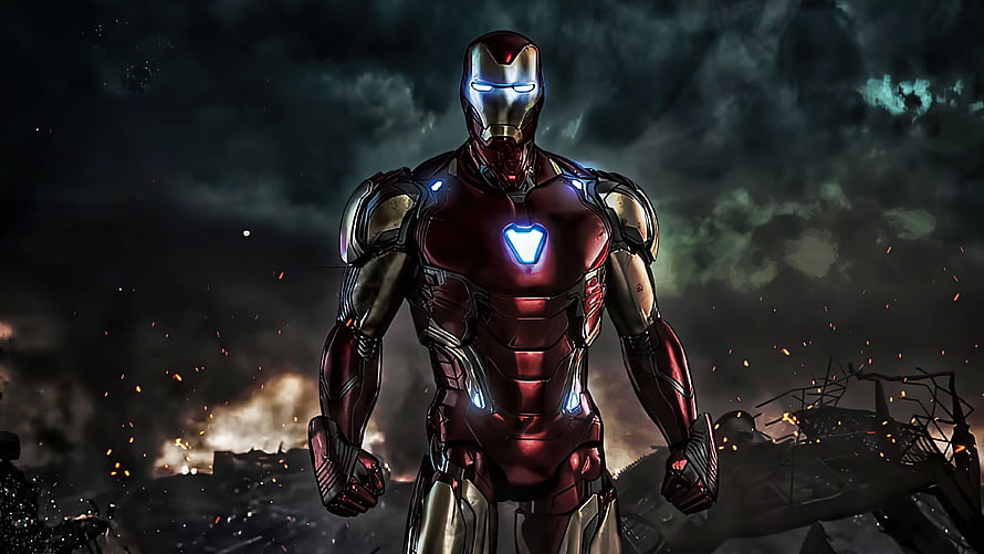 Iron Man Mark 85 Armor Standing in a Dark Battlefield with Glowing Arc Reactor HD wallpaper