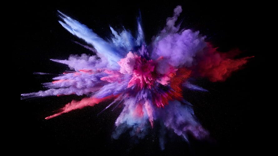 Vibrant multicolored powder explosion frozen in mid-air against a dark background HD wallpaper