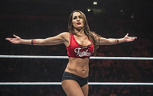 Nikki Bella in red Fearless top and black shorts standing in a wrestling ring with arms outstretched HD wallpaper