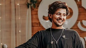 Darshan Raval smiling in black shirt with silver chain necklace at event HD wallpaper