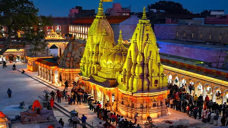 Kashi Vishwanath Temple illuminated at dusk with golden spires and evening crowds HD wallpaper