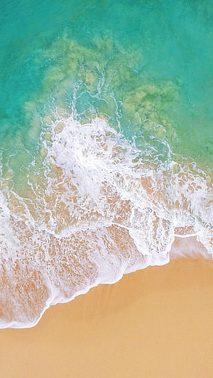 Aerial View of Turquoise Ocean Waves Washing Over Golden Sandy Beach HD phone wallpaper