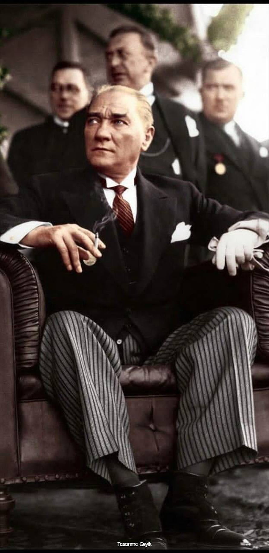 Mustafa Kemal Ataturk in a formal suit seated in a leather armchair holding a cigarette HD phone wallpaper