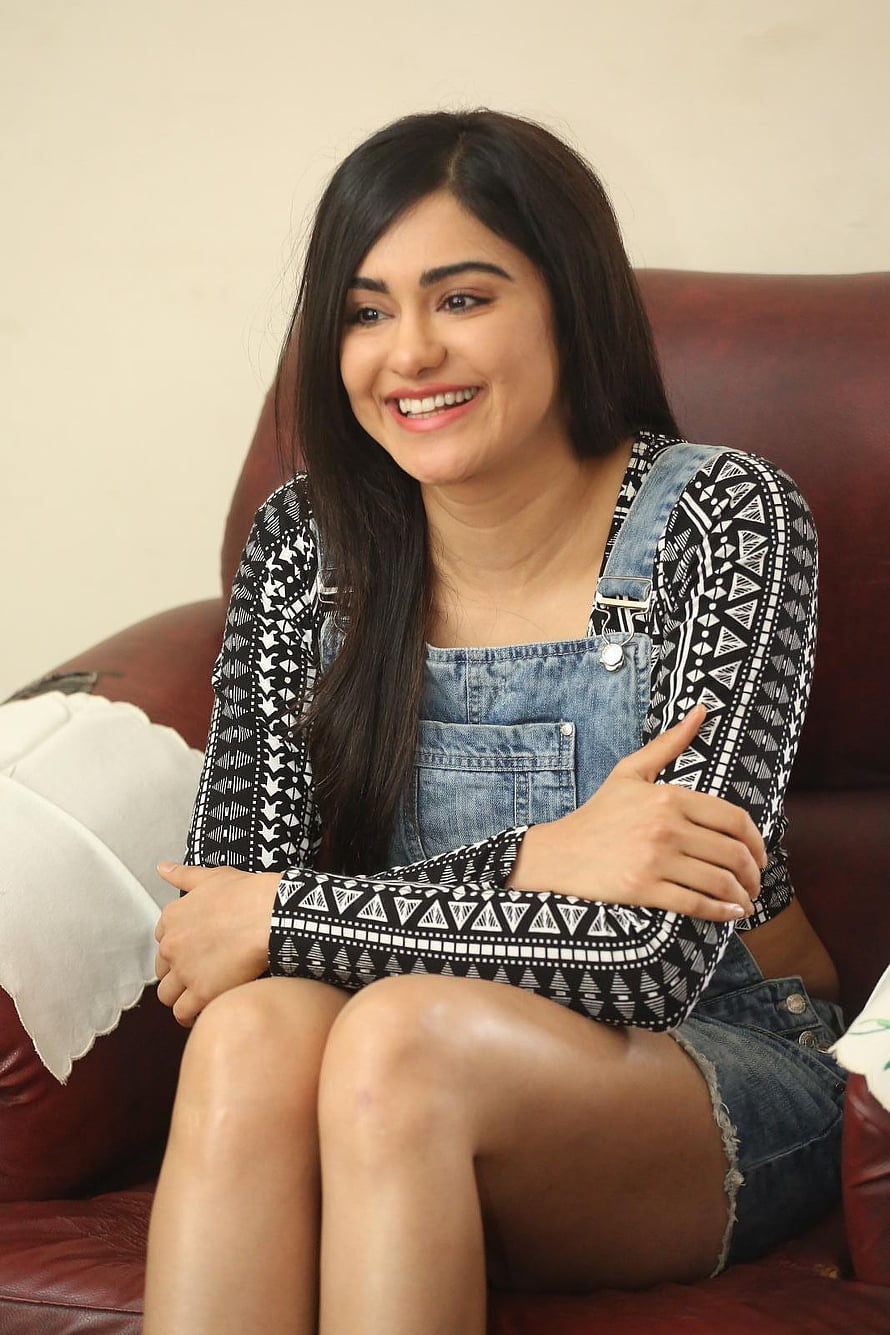Adah Sharma in Denim Overalls and Patterned Top Sitting on Leather Sofa HD phone wallpaper