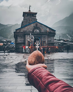 Kedarnath Temple with Trishul and Rudraksha in Hand Against Mountain Backdrop HD phone wallpaper