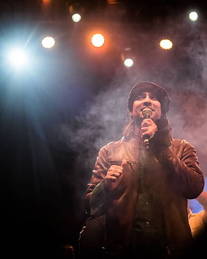 Jubin Nautiyal performing live on stage with microphone under warm concert lighting and atmospheric smoke HD phone wallpaper