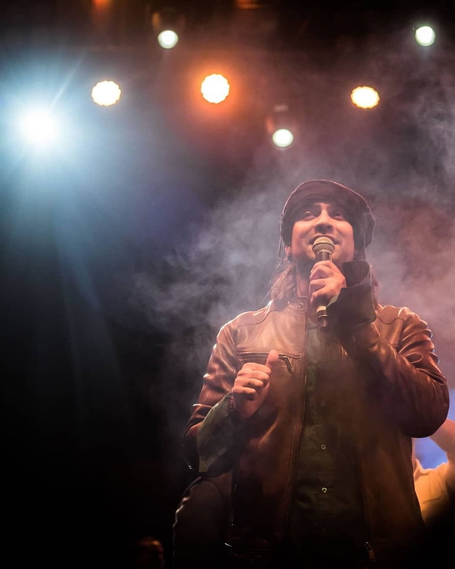 Jubin Nautiyal performing live on stage with microphone under warm concert lighting and atmospheric smoke HD phone wallpaper