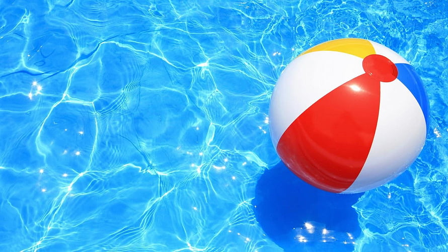 Colorful Beach Ball Floating in Clear Blue Pool Water on a Sunny Summer Day HD wallpaper