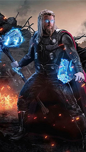 Thor wielding Mjolnir and Stormbreaker in a fiery battlefield with glowing blue lightning effects HD phone wallpaper