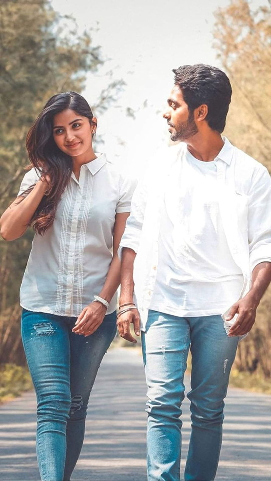 Sivappu Manjal Pachai Movie Still: Couple Walking on a Tree-Lined Path in White Shirts and Jeans HD phone wallpaper