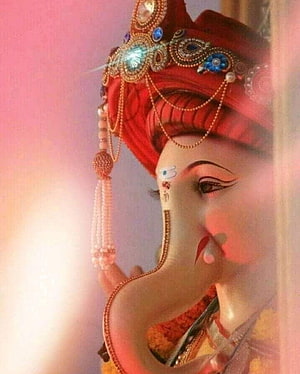 Ganesh deity statue wearing ornate red turban with jeweled ornaments and beaded tassels HD phone wallpaper