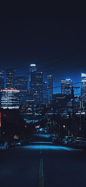 Moody Nighttime Cityscape with Empty Street and Glowing Skyscrapers HD phone wallpaper