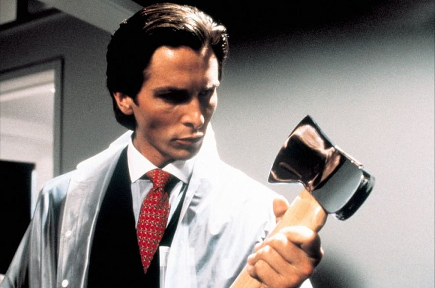 Patrick Bateman from American Psycho holding an axe in a white coat and red tie HD wallpaper