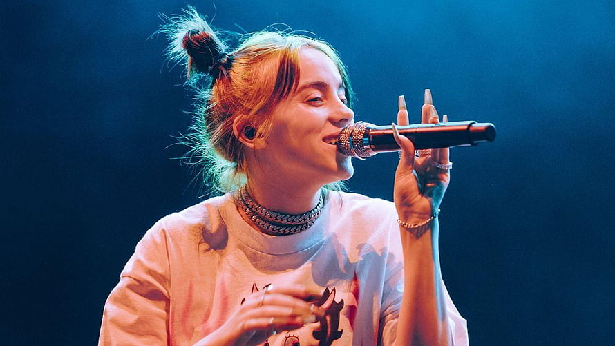 Billie Eilish Performing Live on Stage with Microphone Under Blue Lighting HD wallpaper