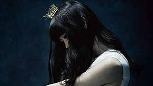 Aimer Portrait with Golden Crown and Long Black Hair in Dramatic Dark Lighting HD wallpaper