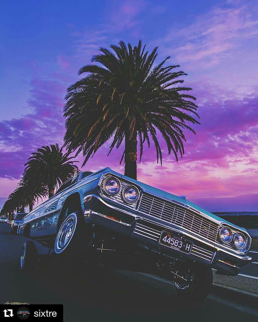 Classic Lowrider Car Parked Under Palm Trees at Sunset with Vibrant Purple Sky HD phone wallpaper