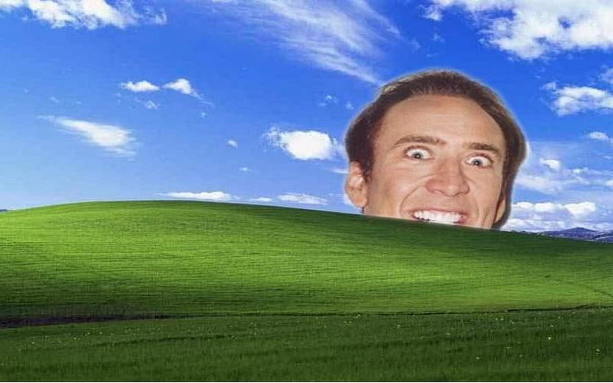 Nicolas Cage Peeking Over a Green Hill in a Blue Sky Landscape HD wallpaper