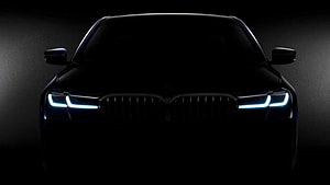 BMW 5 Series Front Facade with Illuminated LED Headlights in Dark Studio Setting HD wallpaper