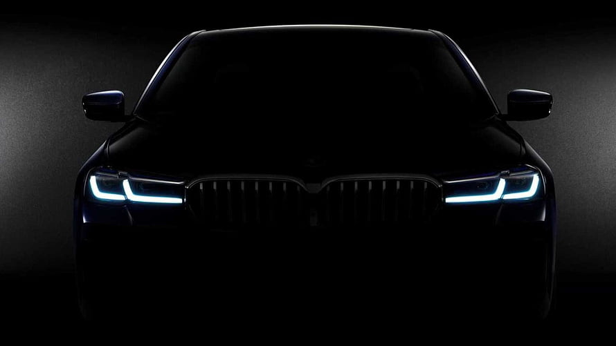 BMW 5 Series Front Facade with Illuminated LED Headlights in Dark Studio Setting HD wallpaper