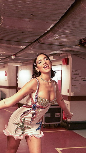 Dua Lipa in a white sequined mini dress with starfish embellishments in an industrial backstage setting HD phone wallpaper