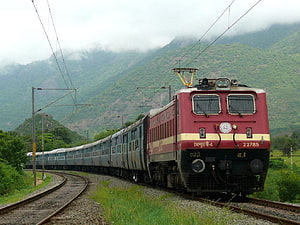 Indian Railways Electric Locomotive 22785 Pulling Passenger Coaches Through Lush Green Mountainous Landscape HD wallpaper