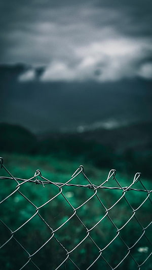 Moody Chain Link Fence Against Dark Stormy Mountain Landscape HD phone wallpaper