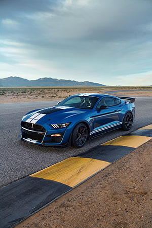 Blue Ford Mustang Shelby GT500 with racing stripes on a desert track HD phone wallpaper
