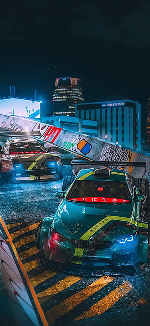 Neon-lit JDM street racing scene with modified BMW and Nissan in a Tokyo night cityscape HD phone wallpaper