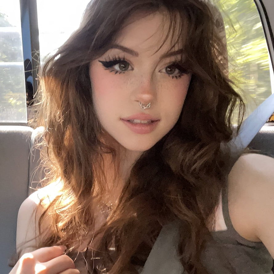 Hannah Owo in a car with long wavy brown hair, dramatic winged eyeliner, and a nose ring HD phone wallpaper