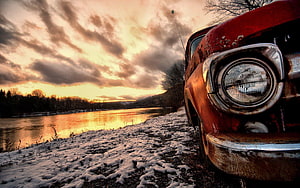 Rusty vintage car parked on a snowy riverbank at golden hour sunset HD wallpaper